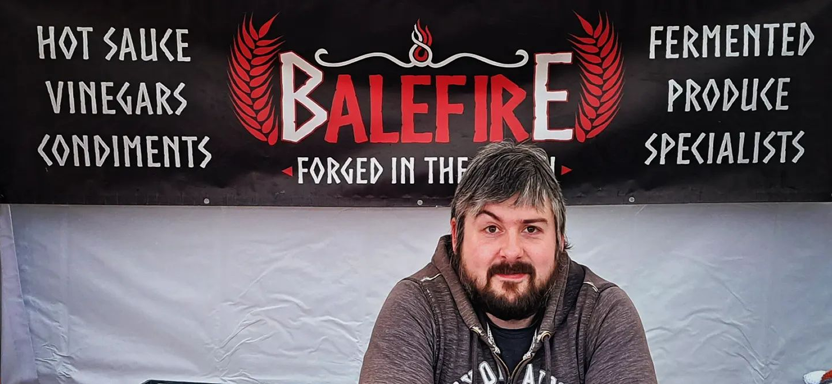 A man in front of a Balefire sign