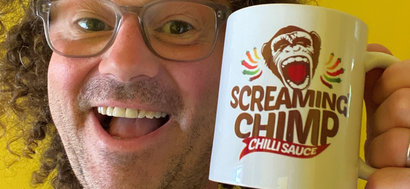Owner of Screaming Chimp holding a mug with the logo on