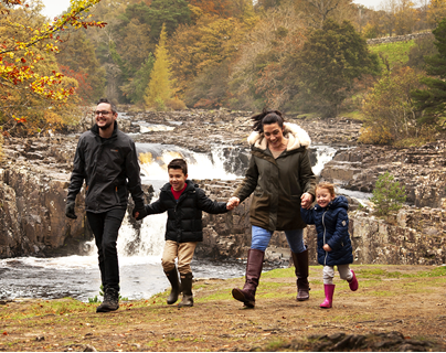 A family walking at High Force in autumn