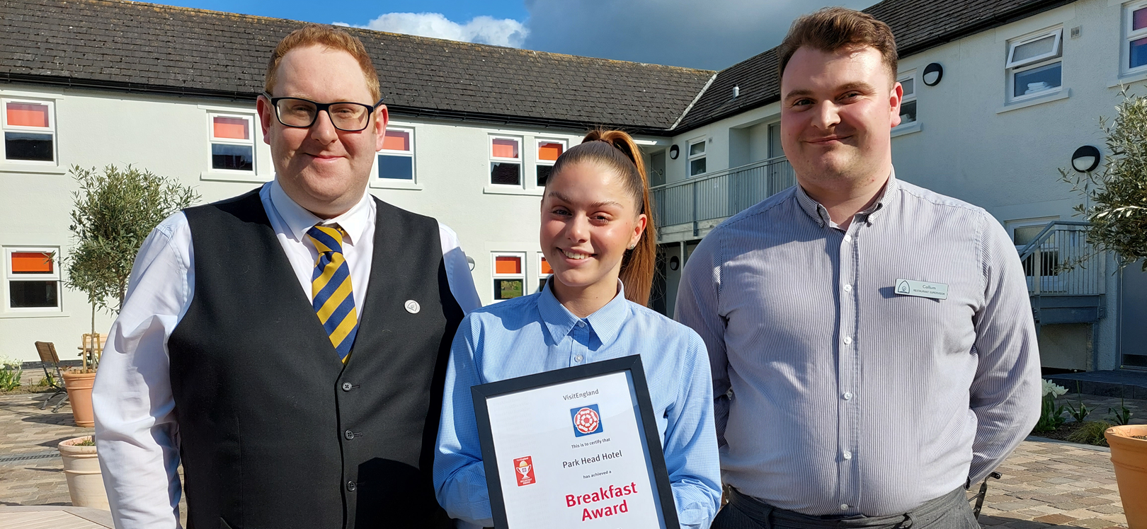 Three people stood outside of Park Head Hotel with an award