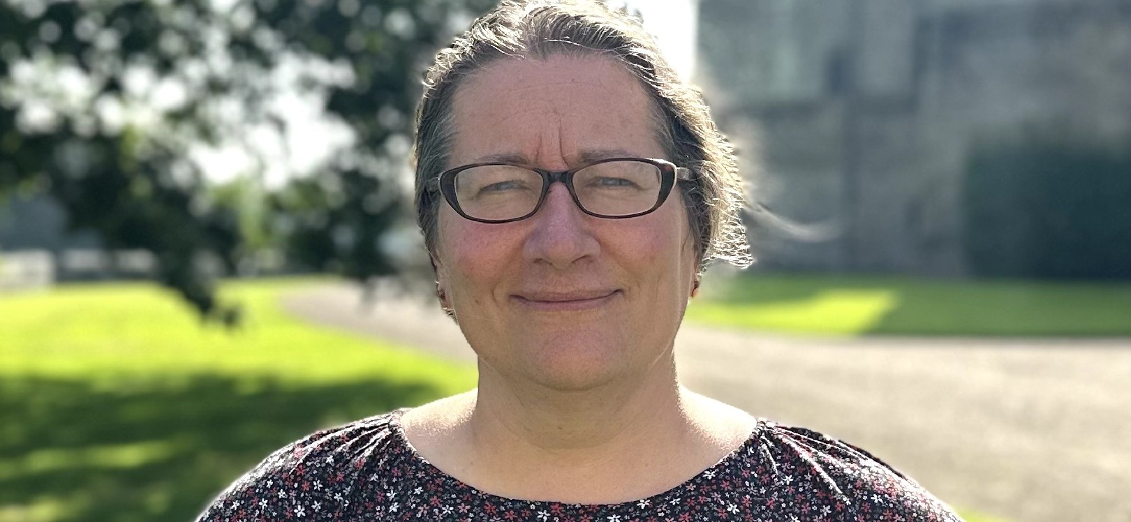 A portrait photograph of Victoria Cadman, Raby Estate's new sustainability manager. Victoria has her hair tied back and is wearing glasses. She is smiling at the camera.