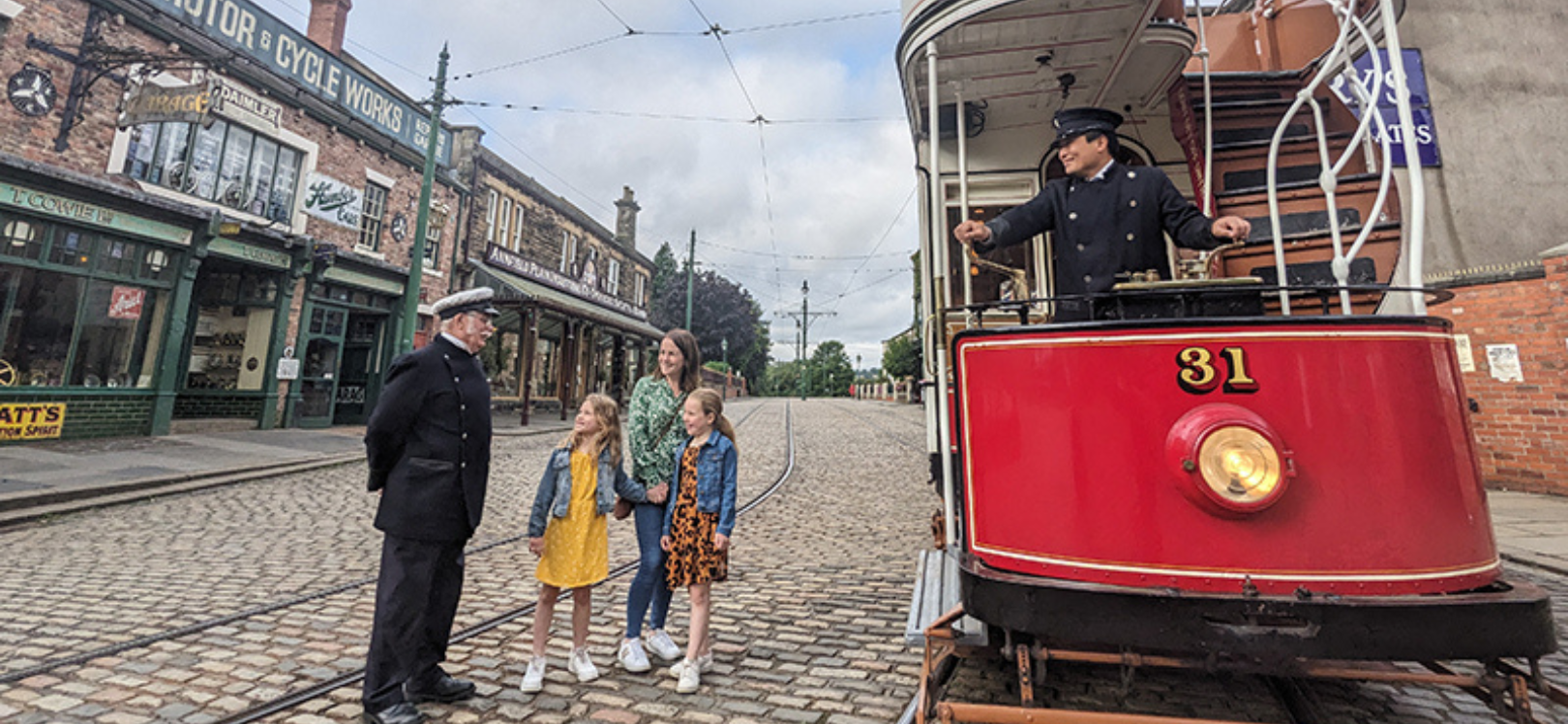 A family stood next to a tram at Beamish Museum