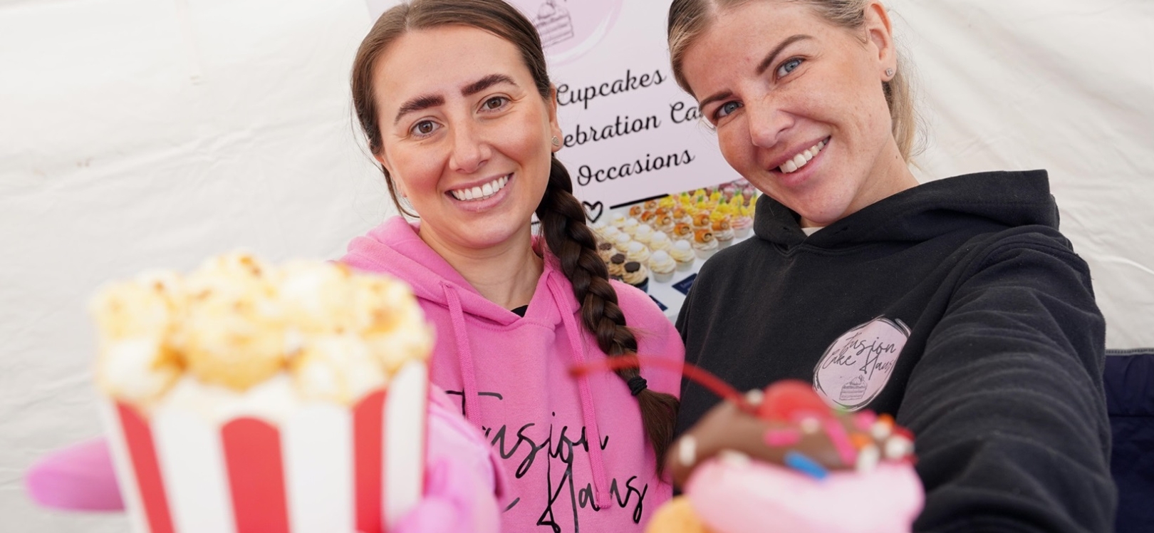 Two women holding up cupcakes