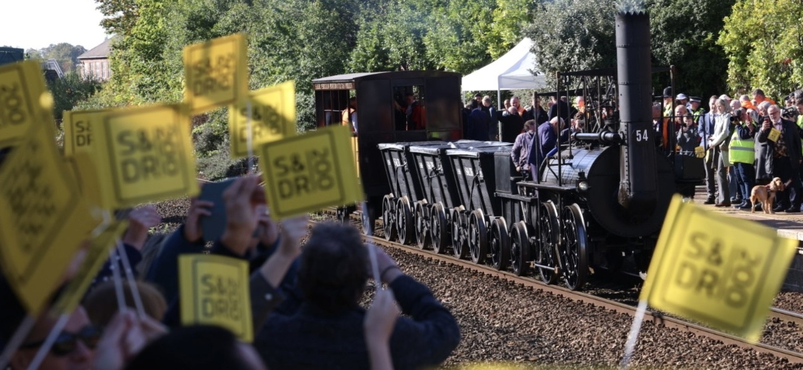 People waving flags next to a train